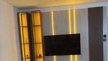 Een moderne woonkamer met een flatscreen-televisie bevestigd aan een houten wand, verlicht door verticale LED-verlichting.