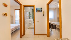 Ein Flur mit einem Bett, einem Schreibtisch und einem an der Wand befestigten Telefon.