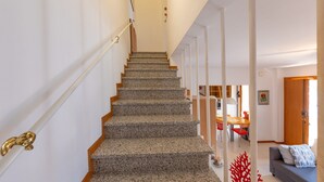 Eine Treppe mit Handlauf, die zu einem Essbereich mit Stühlen und Tisch führt.