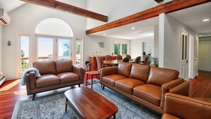 A spacious living room with leather sofas, a wooden coffee table, and a dining area with a table and chairs. - Ocean Views & Private Beach 3br Nature Escape 3 Bedroom Villa (Plymouth)