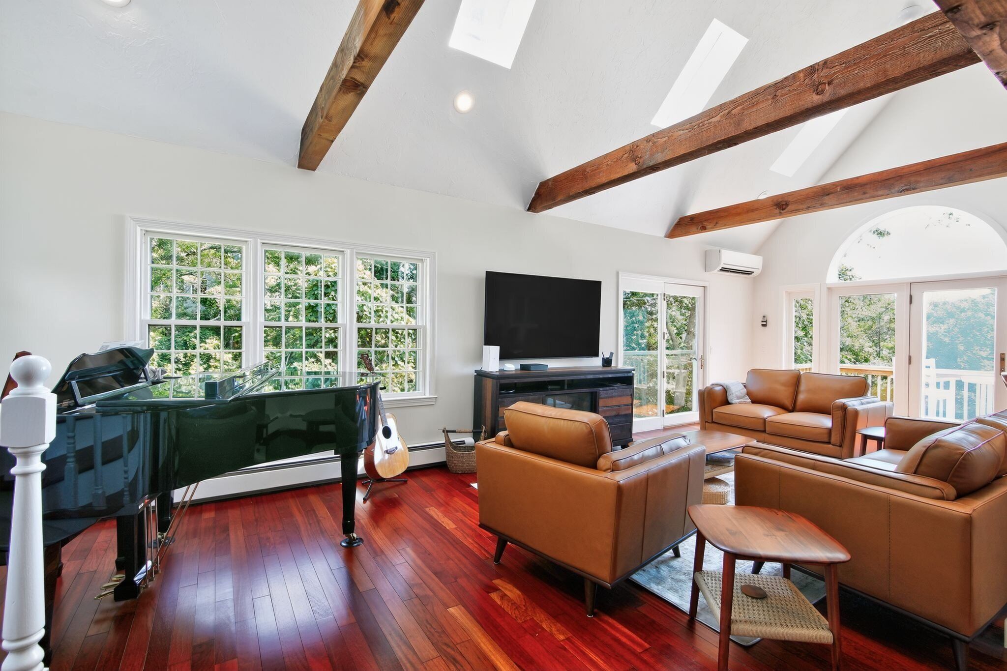 A spacious living room with a grand piano, a television, and comfortable seating.