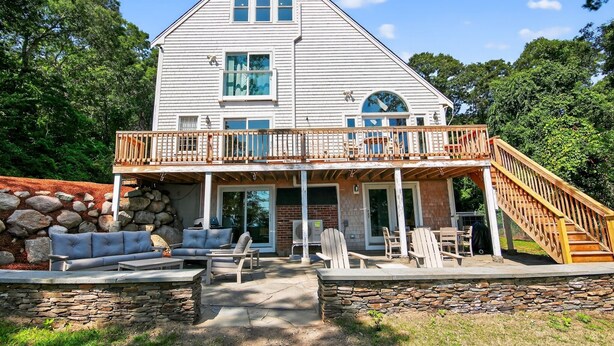 A two-story house with a covered patio, stone walls, and a wooden staircase. - Ocean Views & Private Beach 3br Nature Escape 3 Bedroom Villa (Plymouth)