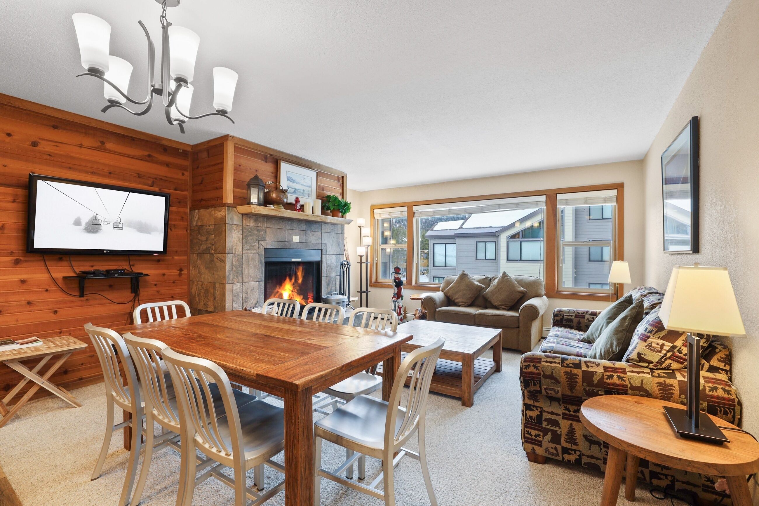 A cozy living room with a fireplace, a dining area, and a sofa with a patterned throw.