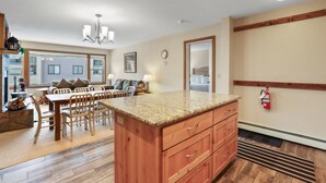 A spacious kitchen with a granite countertop, wooden cabinets, and a dining area with a table and chairs.