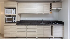 A compact kitchen with a microwave, stove, sink, and light wood cabinetry. - 3BR Apt w/ BBQ 290m From Beach Pic0125 (Bombinhas)