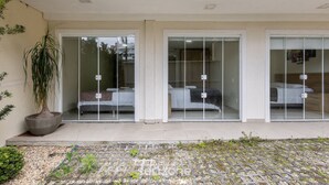 A hotel with three rooms, each with a bed and a window. There is a potted plant outside. - 3BR Apt w/ BBQ 290m From Beach Pic0125 (Bombinhas)
