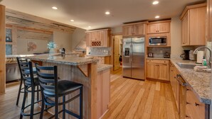 A modern kitchen with wooden cabinets, a stainless steel refrigerator, and a granite countertop. - The Westlands Lodge 1135ac 4 Bedroom Home (South Lake Tahoe)