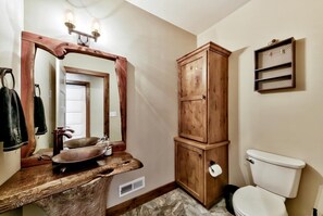 A bathroom with a wooden vanity, a sink, a mirror, a cabinet, and a toilet. - 1008c Mountain View Retreat 5 Bedroom Home (South Lake Tahoe)