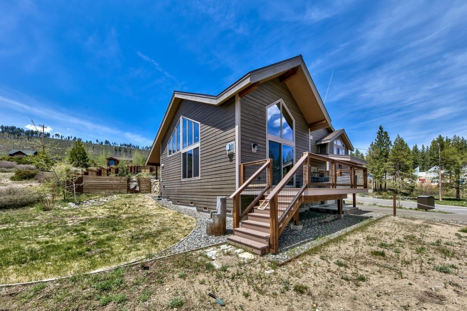 A two-story house with a wooden deck and a staircase leading to the entrance.