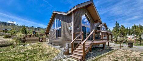 A two-story house with a wooden deck and a staircase leading to the entrance.