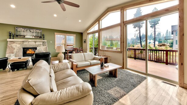 A spacious living room with a fireplace, leather sofas, a coffee table, and large windows offering a view of the outdoors. - 1376md Angora View 4 Bedroom Home (South Lake Tahoe)