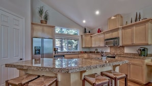 A spacious kitchen with a large island, wooden cabinets, and a window providing natural light. - 1272g Where Eagles Fly 3 Bedroom Home (South Lake Tahoe)