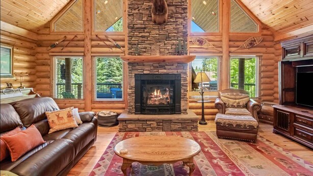 A log cabin interior with a stone fireplace, leather furniture, and large windows. - Nature's Delight, Private Family-Friendly Cabin (McCall)