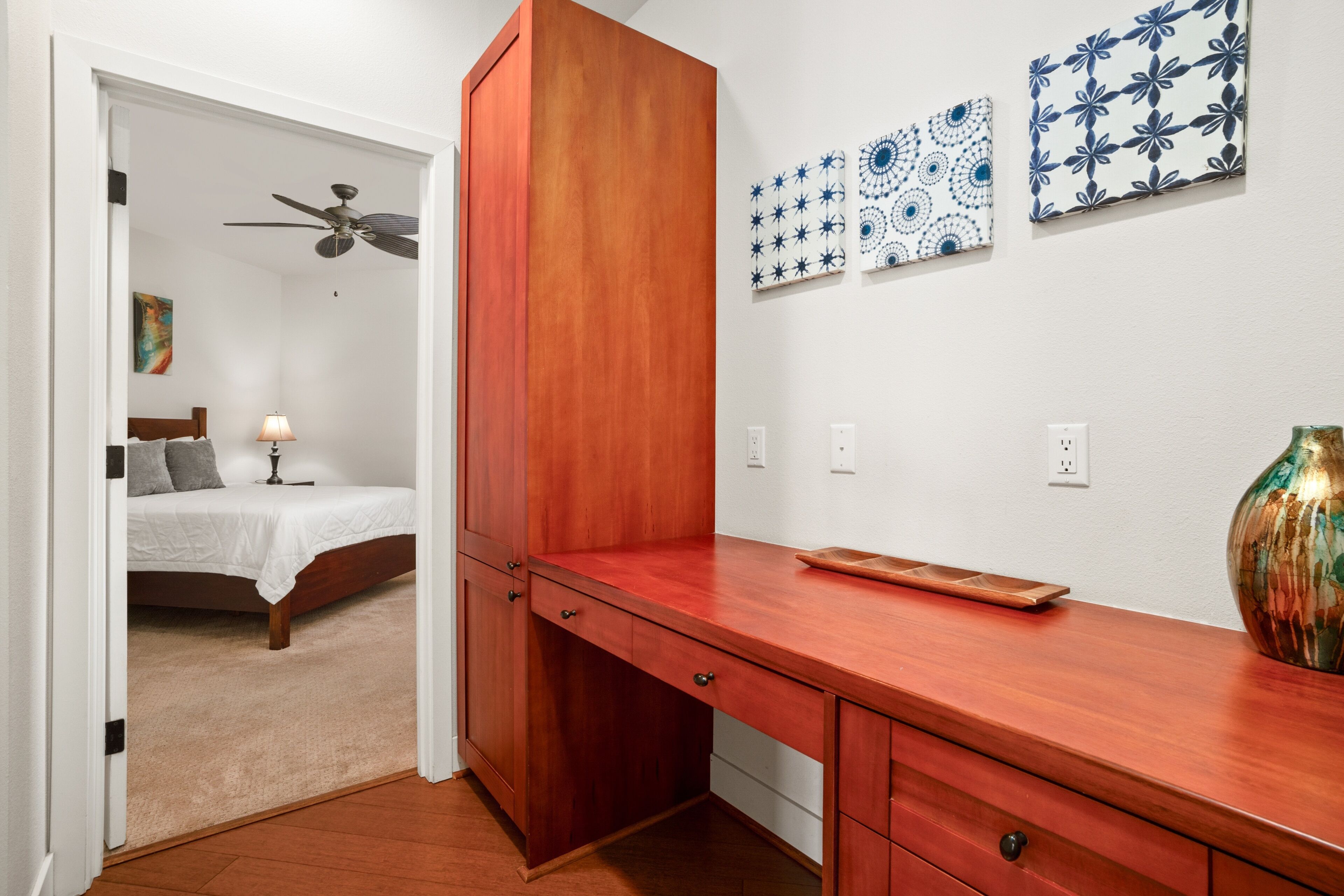 A bedroom with a bed, a nightstand, a ceiling fan, and a nightlight.