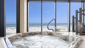 A hot tub with a marble design, located in a room with large windows overlooking a beach. - Phoenix Ii 2151 3 Bedroom Condo (Orange Beach)