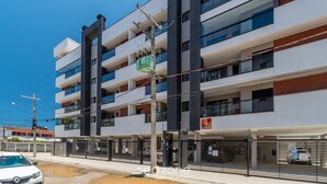 A multi-story building with balconies, a covered parking area, and a visible sign for a business named "SUMMER". - Apto Recanto das Aves a 450m da Praia PHA0023 (Ubatuba)