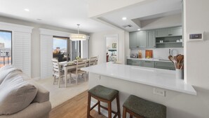 Una cocina moderna con una isla central, armarios blancos y un comedor con mesa y sillas.