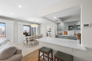 Une cuisine moderne dotée d’un îlot central, de meubles blancs et d’un coin repas avec une table et des chaises.