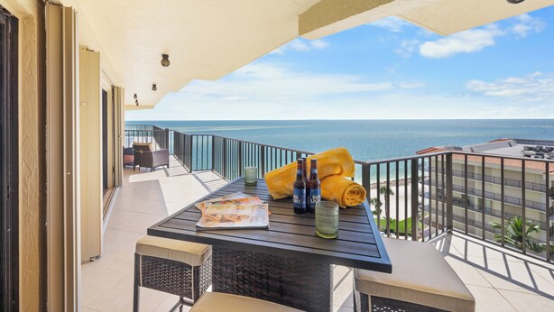 A balcony with a table, chairs, and a view of the ocean. - Rare Desirable Unit | Located in Shipps Landing III (Marco Island)