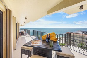 A balcony with a table, chairs, and a view of the ocean. - Rare Desirable Unit | Located in Shipps Landing III (Marco Island)