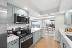 A modern kitchen with stainless steel appliances, light blue cabinets, and a large island. - Rare Desirable Unit | Located in Shipps Landing III (Marco Island)