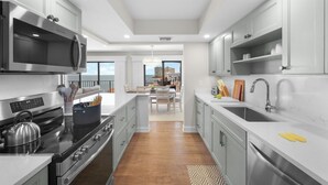 A modern kitchen with stainless steel appliances, a large island, and a view to the dining area. - Rare Desirable Unit | Located in Shipps Landing III (Marco Island)