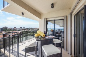 A balcony with wicker furniture, a table, and a view of the cityscape. - Rare Desirable Unit | Located in Shipps Landing III (Marco Island)