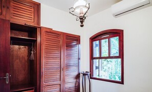 A room with wooden doors, a window with a view of greenery, and a ceiling light fixture.