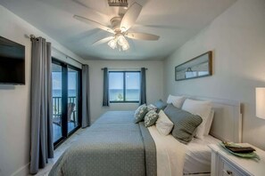 A bedroom with a bed, a nightstand, a ceiling fan, a window, and a view of the outdoors.
