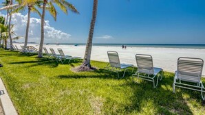 Une plage bordée de palmiers, avec des chaises longues et une vue dégagée sur l’océan.