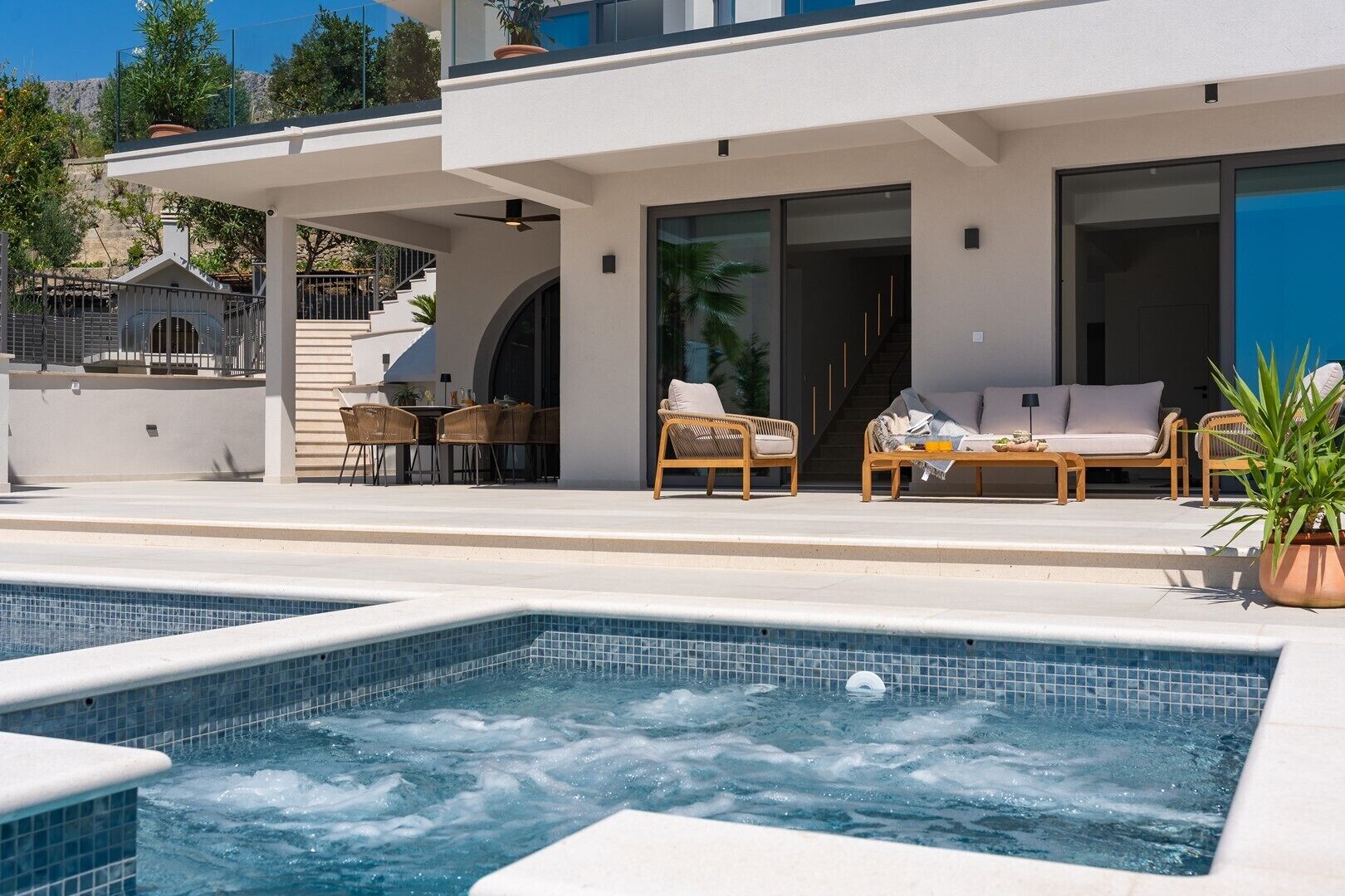 Une maison moderne dotée d’une piscine, d’un espace salon extérieur et d’un escalier menant à un deuxième étage.