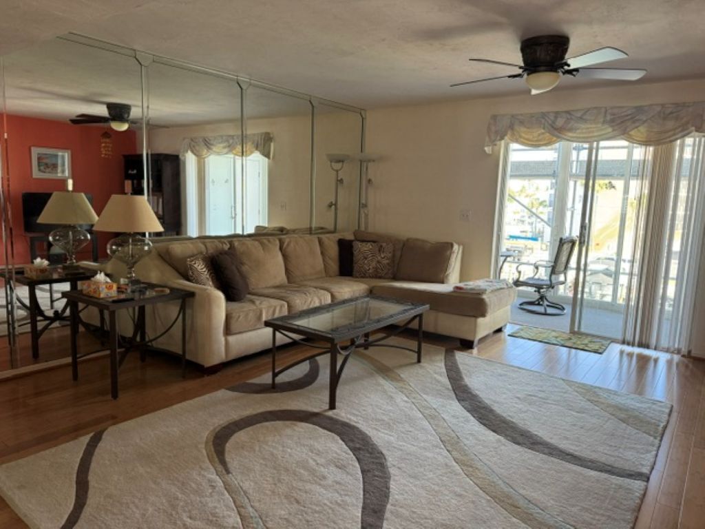 A living room with a sectional sofa, a glass coffee table, a lamp, and a large mirror.