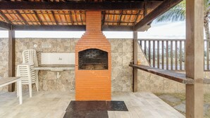 Een terras buiten met een bakoven, stenen muren en een houten pergola.