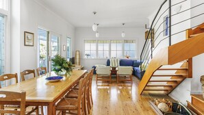 Amplia sala de estar con una mesa de comedor de madera, sillas, sofá y una escalera.