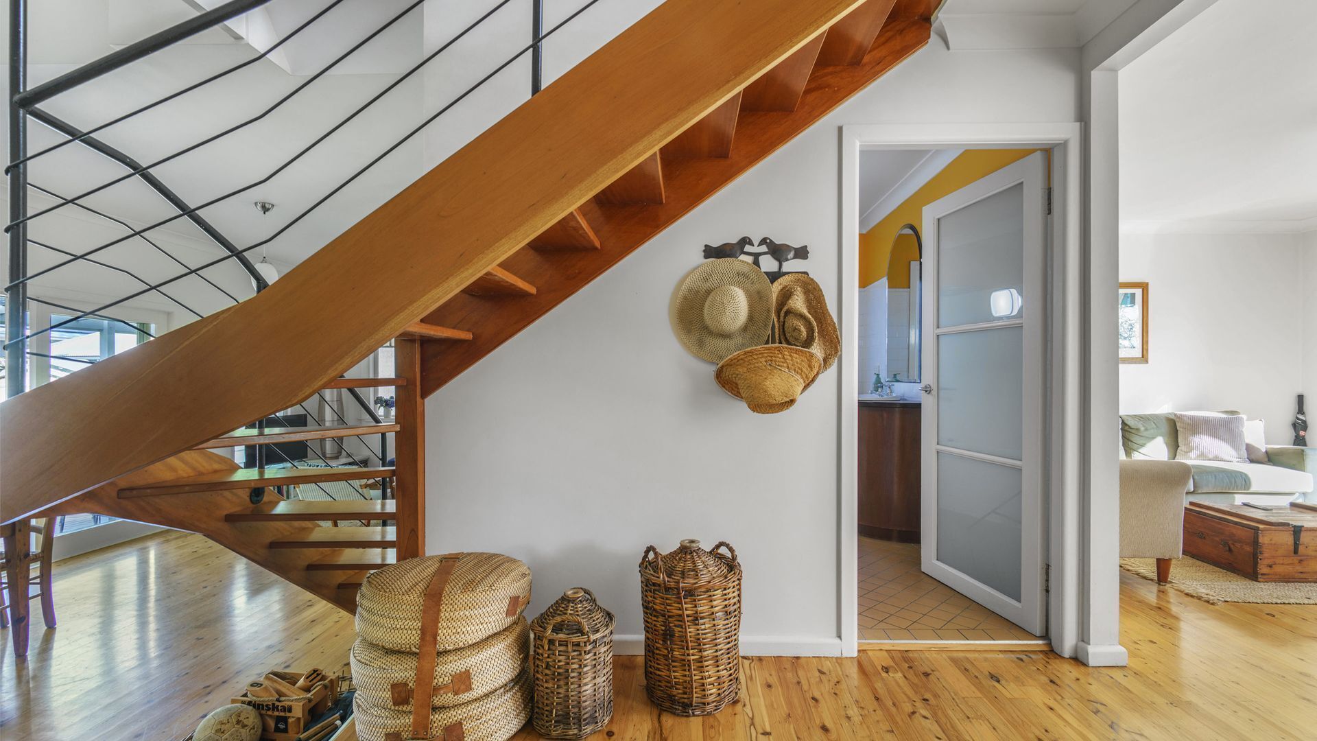Ein geräumiges Zimmer mit einer Holztreppe, einem Essbereich und Blick auf die Küche.