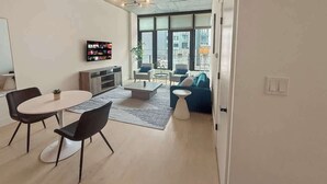 Una sala de estar moderna con comedor, ventanas amplias y una vista panorámica de la ciudad.