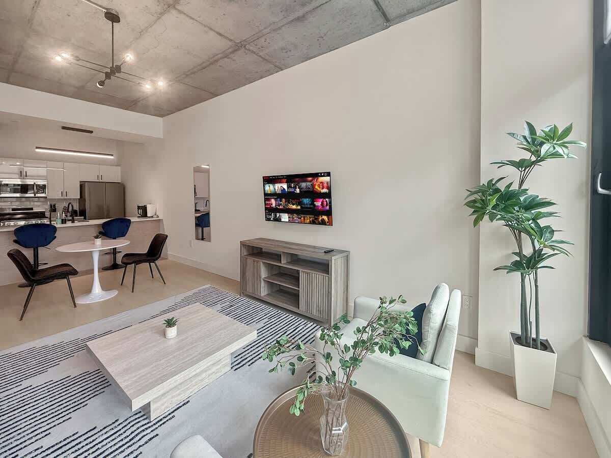 A modern living room with a dining area, a fireplace, and a large TV mounted on the wall.