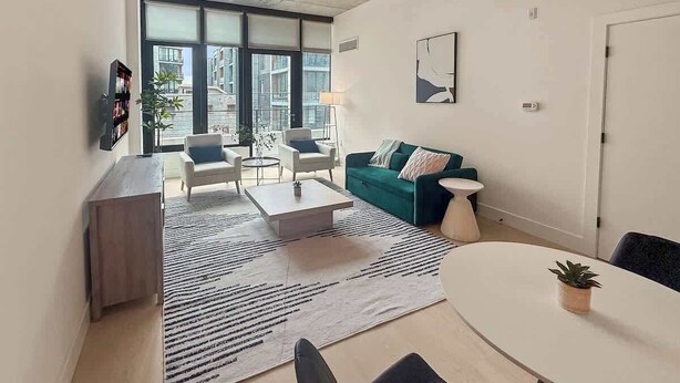 Una sala moderna con un sofá, sillas, una mesa de centro y una mesa de comedor.