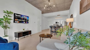 Una sala de estar moderna con un televisor de pantalla plana, un comedor y una cocina.