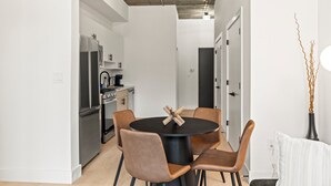 Une cuisine moderne avec une table à manger ronde et des chaises, un réfrigérateur et une machine à café.