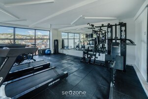 Un gimnasio con caminadora, máquinas de pesas y pelotas de ejercicio.
