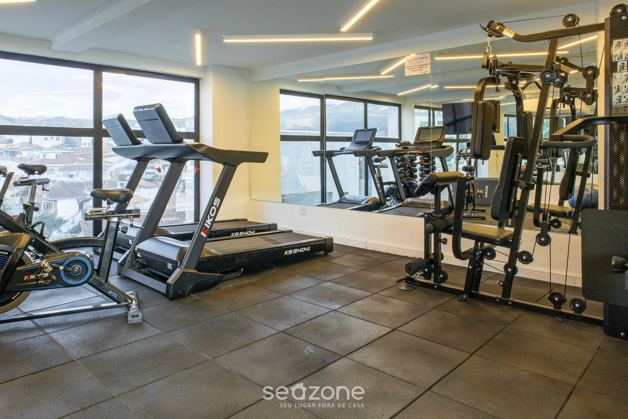 Un gimnasio con cintas de correr, bicicletas estáticas y máquinas de pesas.