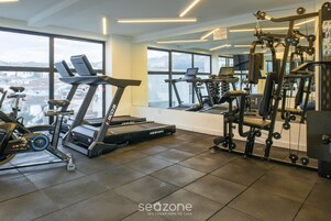 Un gimnasio con cintas de correr, bicicletas estáticas y máquinas de pesas.