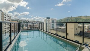 A rooftop pool with a clear view of surrounding buildings and a hilly landscape. - Your Complete Stay With Pool and gym in Pocos de Caldas - NGO (Poços de Caldas)