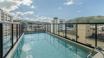 A rooftop pool with a clear view of surrounding buildings and a hilly landscape.