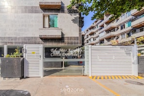 A gated entrance to Ed. Mar Azuleta Costa Dourada, featuring a metal gate and a sign with the property name.