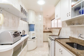 A modern kitchen with white cabinets, a granite countertop, a built-in oven, and a water dispenser.