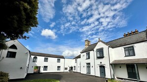 A courtyard with white buildings, a paved walkway, and a clear blue sky. - Rhode Lane Serviced Apartments (Bridgwater)