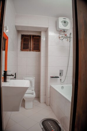 A small, modern bathroom with a toilet, sink, and shower. - Serene Annex Hotel and Apartment (Dar es Salaam)