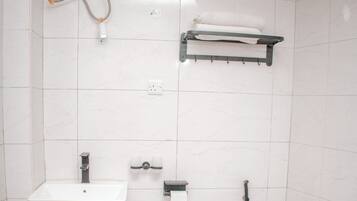 Un baño con inodoro, lavamanos y perchero para toallas.